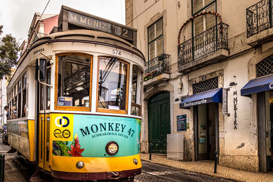 A vibrant Lisbon tram passes through a historic street, capturing the essence of Portugal's urban life.