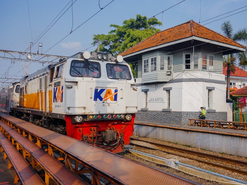 A commuter train arrives at a station in Jakarta, Indonesia, with a sign visible.