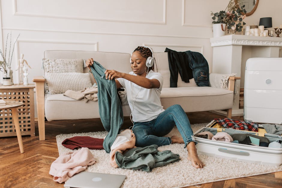 Woman packing clothes in a suitcase while listening to music at home.