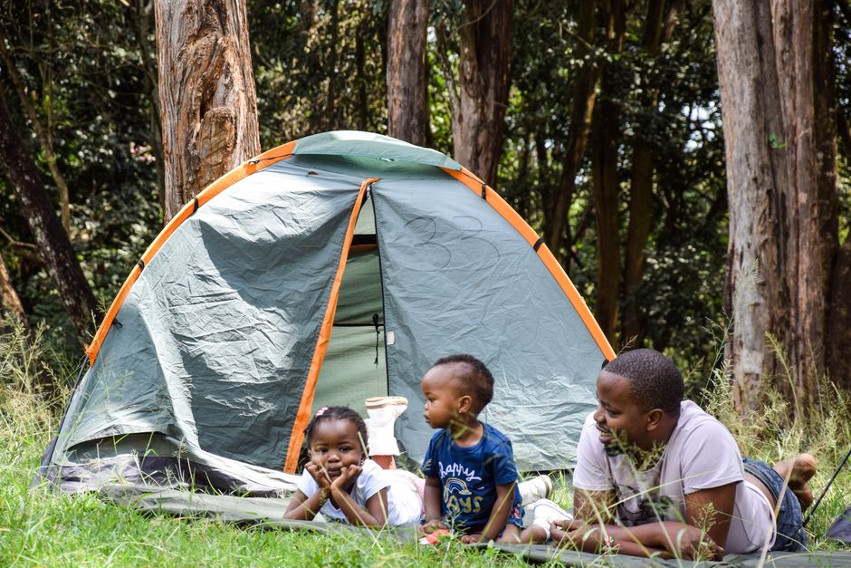 Father and children enjoying a camping trip in a lush Kenyan forest. Perfect family bonding time.