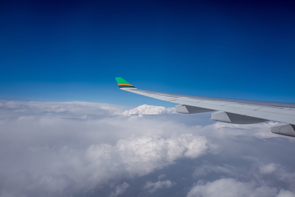 A stunning view from an airplane wing above fluffy white clouds and a deep blue sky.