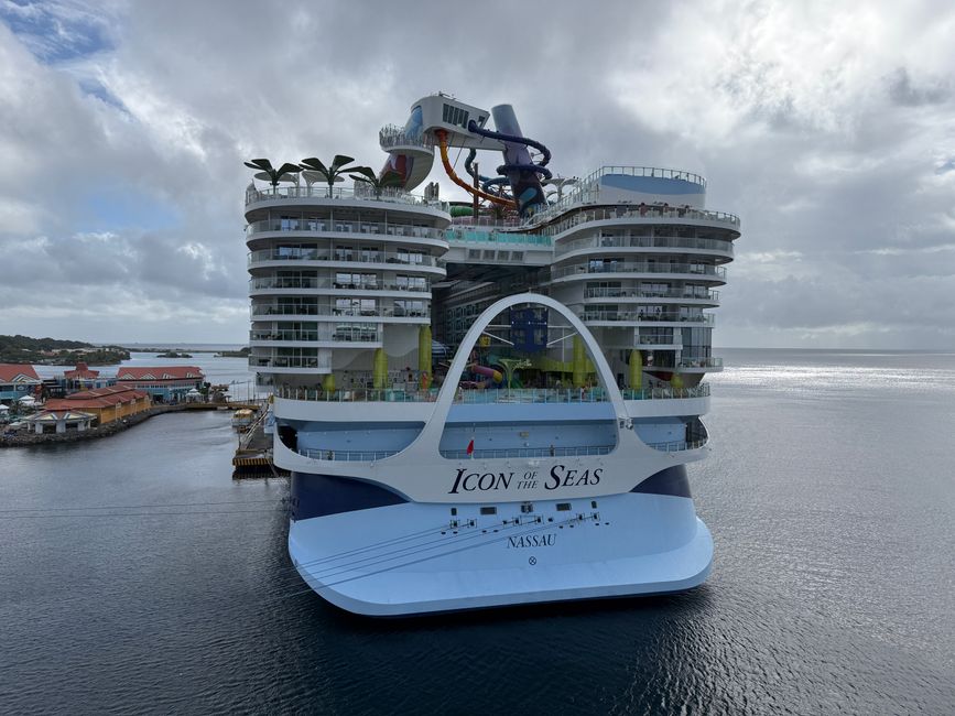 View of Icon of the Seas cruise ship docked at a harbor under cloudy skies.