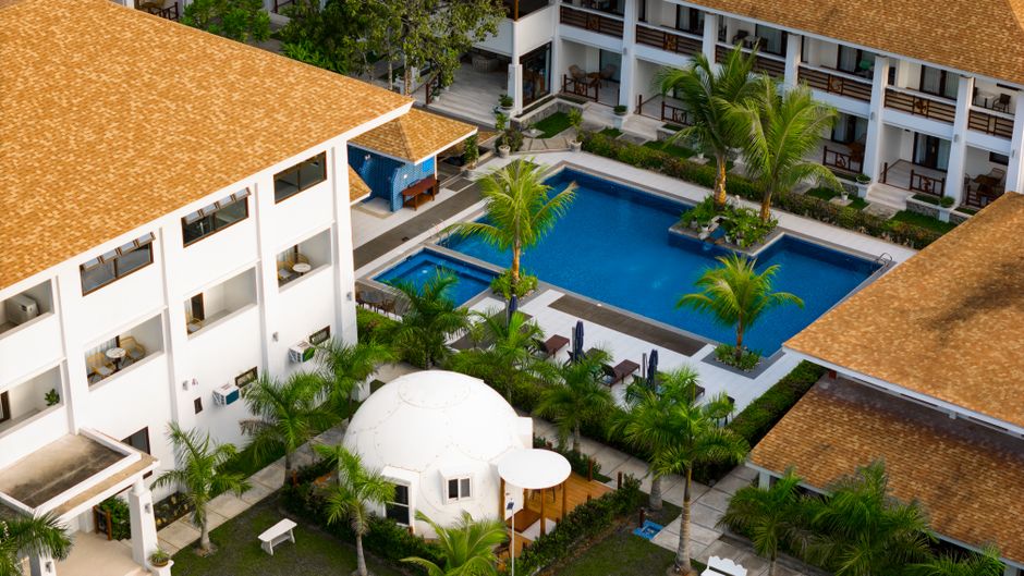 Stunning aerial view of a tropical resort in El Nido with pool and lush palm trees.
