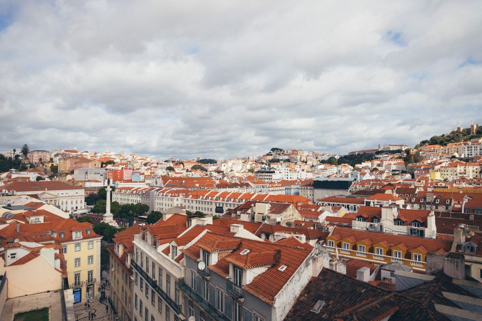 A picturesque aerial view of Lisbon, showcasing its iconic red rooftops and historic architecture on a cloudy day.