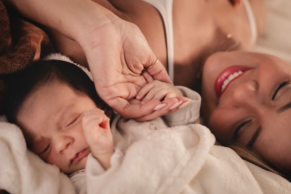 A mother and her newborn holding hands, capturing a tender moment of love.