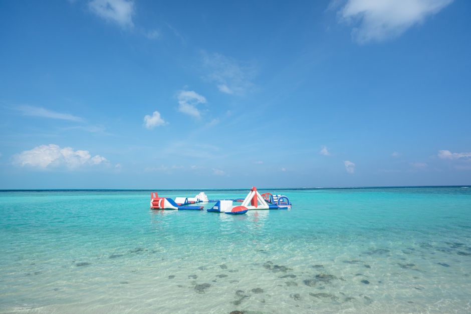 Vibrant inflatable obstacle course floating on turquoise water at a serene tropical beach.