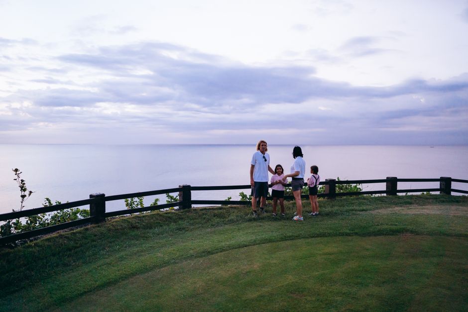 A family of four enjoying a serene summer evening by the coast with a beautiful ocean view.