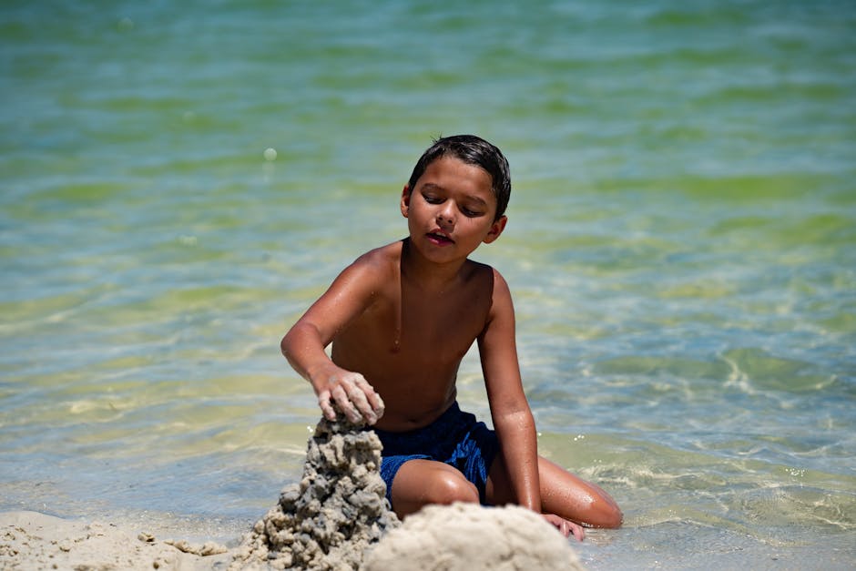 Young boy enjoying a sunny day building a sandcastle on a beach in Hudson, Florida.