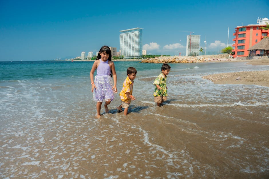 Children enjoying a sunny day at the beach with clear skies and gentle waves.