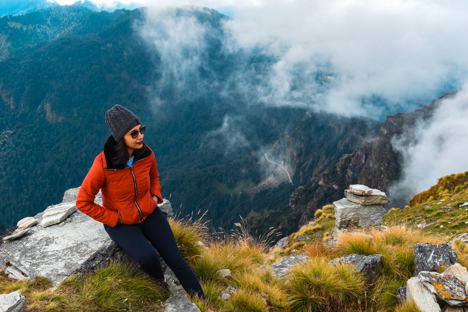 Woman enjoys a break while hiking in the picturesque Chopta mountains, India.
