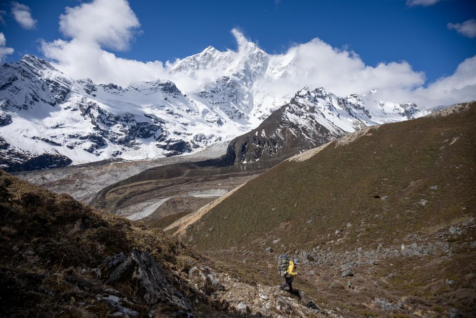 Backpacker trekking through remote snowcapped mountain landscape on a clear day.