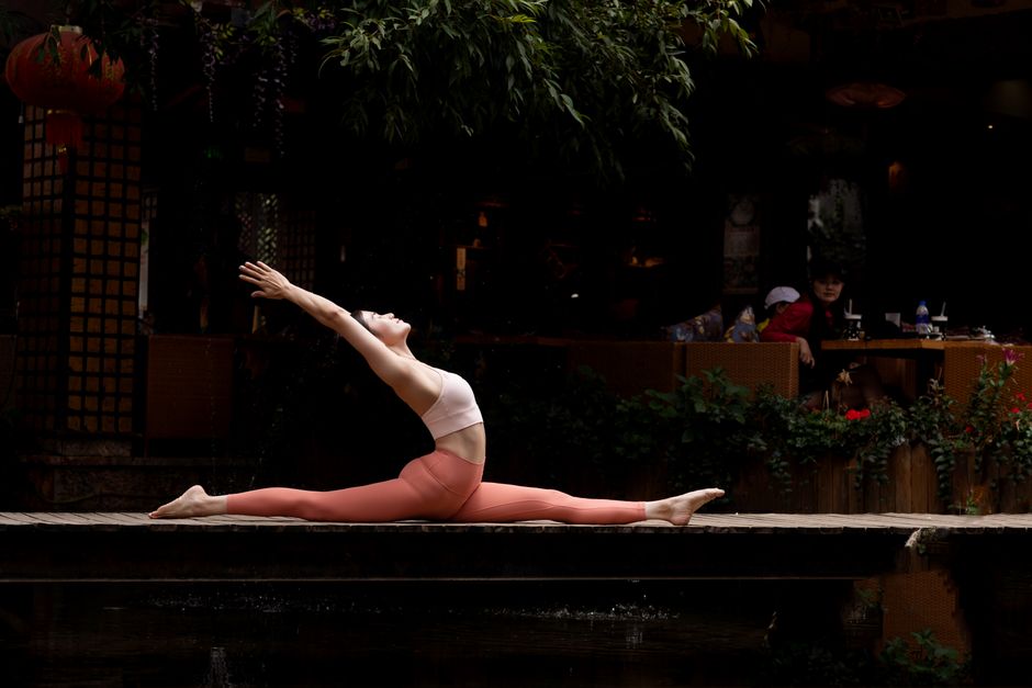 A woman practicing yoga in a peaceful outdoor environment, showcasing flexibility and balance.