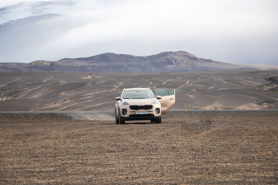Kia Sportage parked on the rugged terrain of Iceland's highlands under vast open skies.
