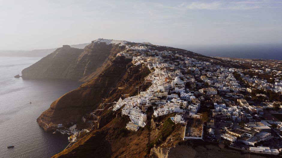 Breathtaking aerial view of Fira, Greece showcasing stunning clifftop architecture during sunset.