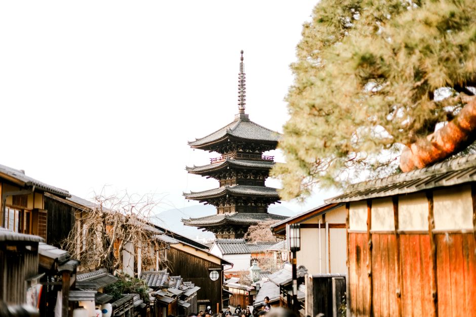 View of a pagoda in Kyoto surrounded by traditional wooden buildings and trees.