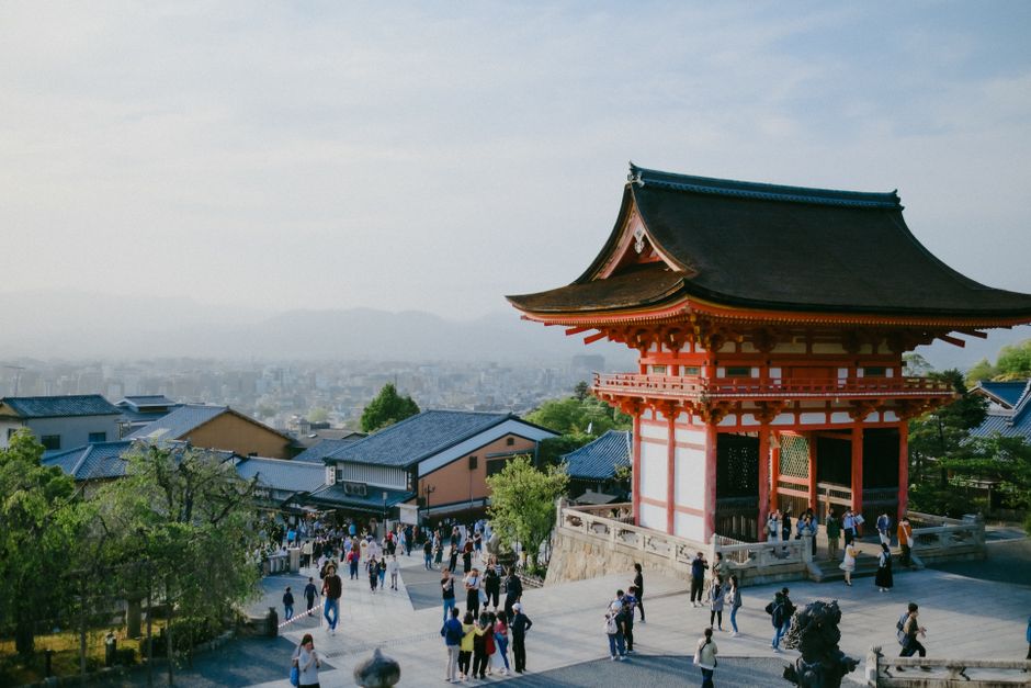Kiyomizu-Dera Temple in Kyoto with cityscape in background, capturing cultural and urban blend.