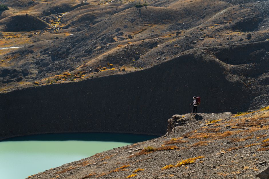 A lone hiker stands on a cliff, overlooking a stunning glacier lake in Wyoming.