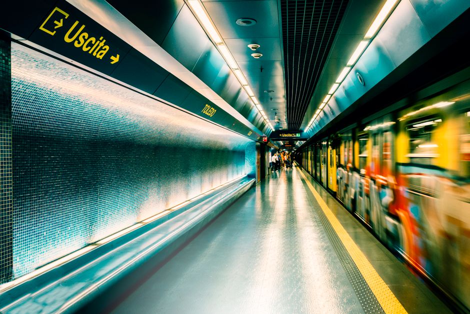 Dynamic scene of a subway station in Napoli with a moving train and illuminated signage.