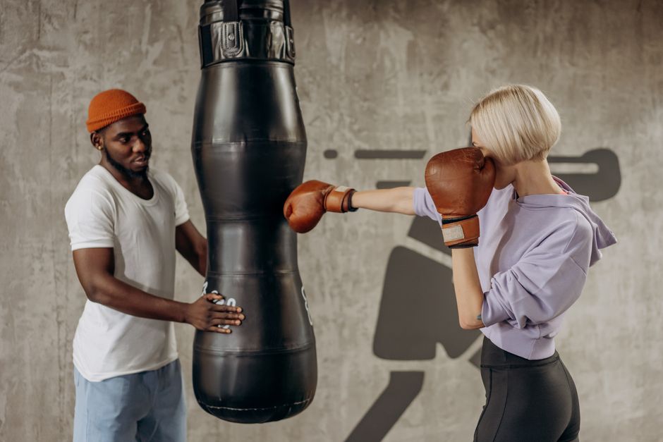 A woman boxing with a trainer in an indoor gym, focusing on technique and strength.