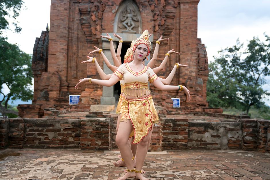 Group of women performing a traditional cultural dance in front of an ancient temple.