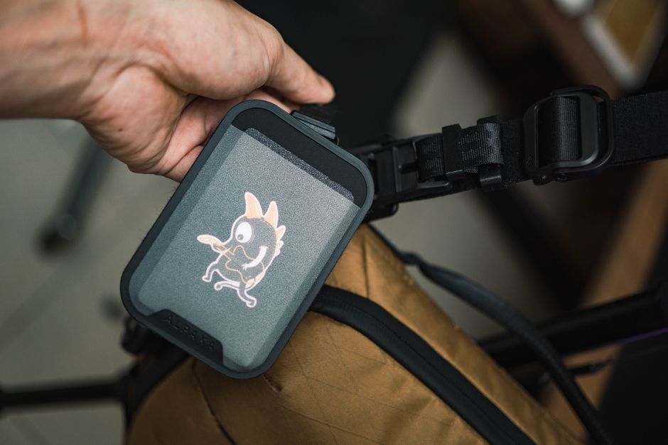 Close-up of a hand holding a backpack with a whimsical character sticker, highlighting stylish accessory.