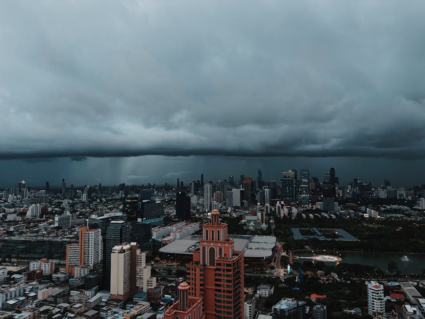 Aerial view of Bangkok's urban skyline under dark storm clouds, capturing the city's dramatic atmosphere.