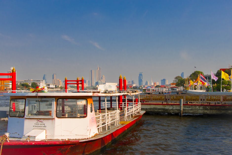 Docked boat on Chao Phraya River with Bangkok's skyline in the background, emphasizing urban contrast.